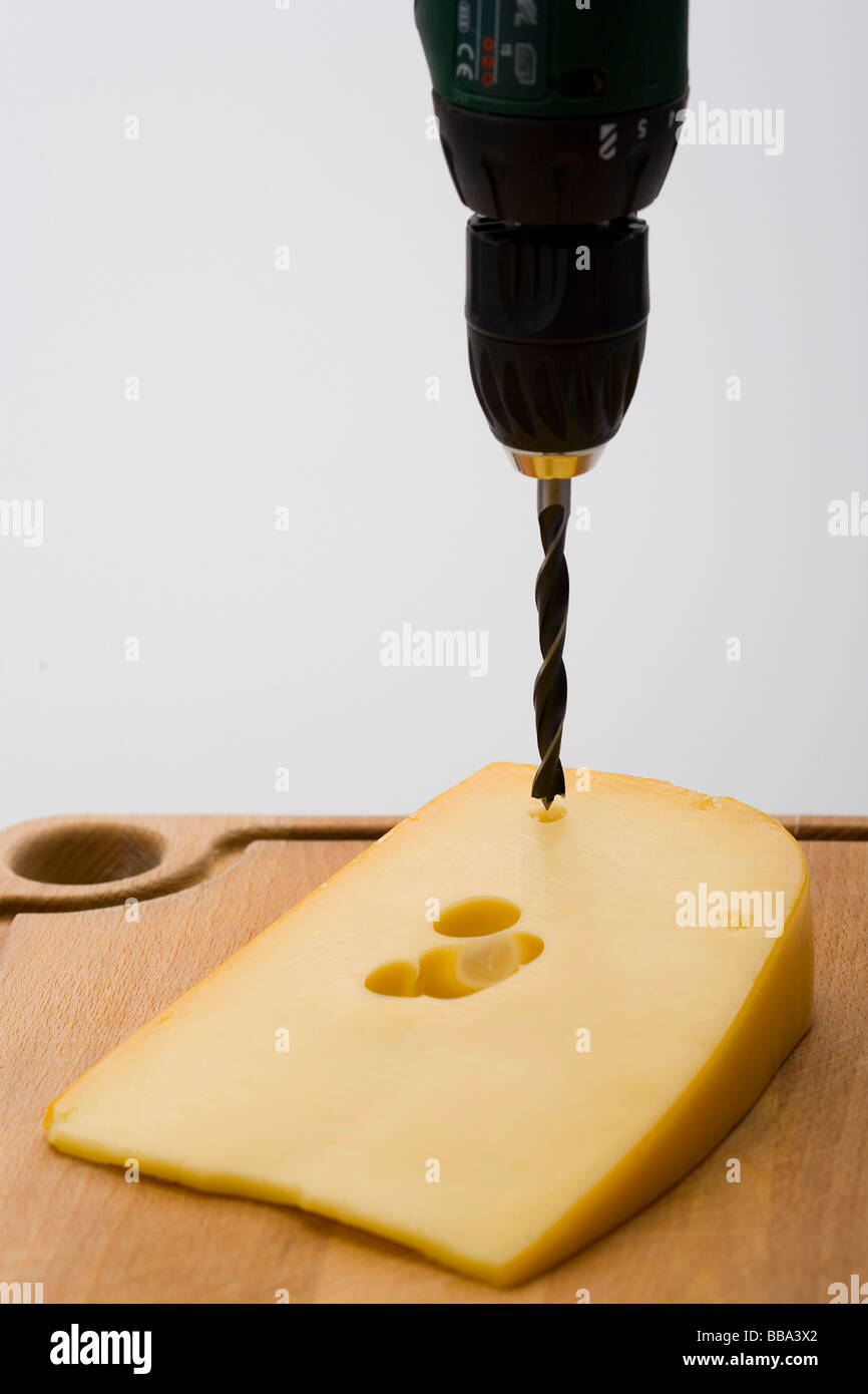 Taladrar los agujeros en el queso Foto de stock