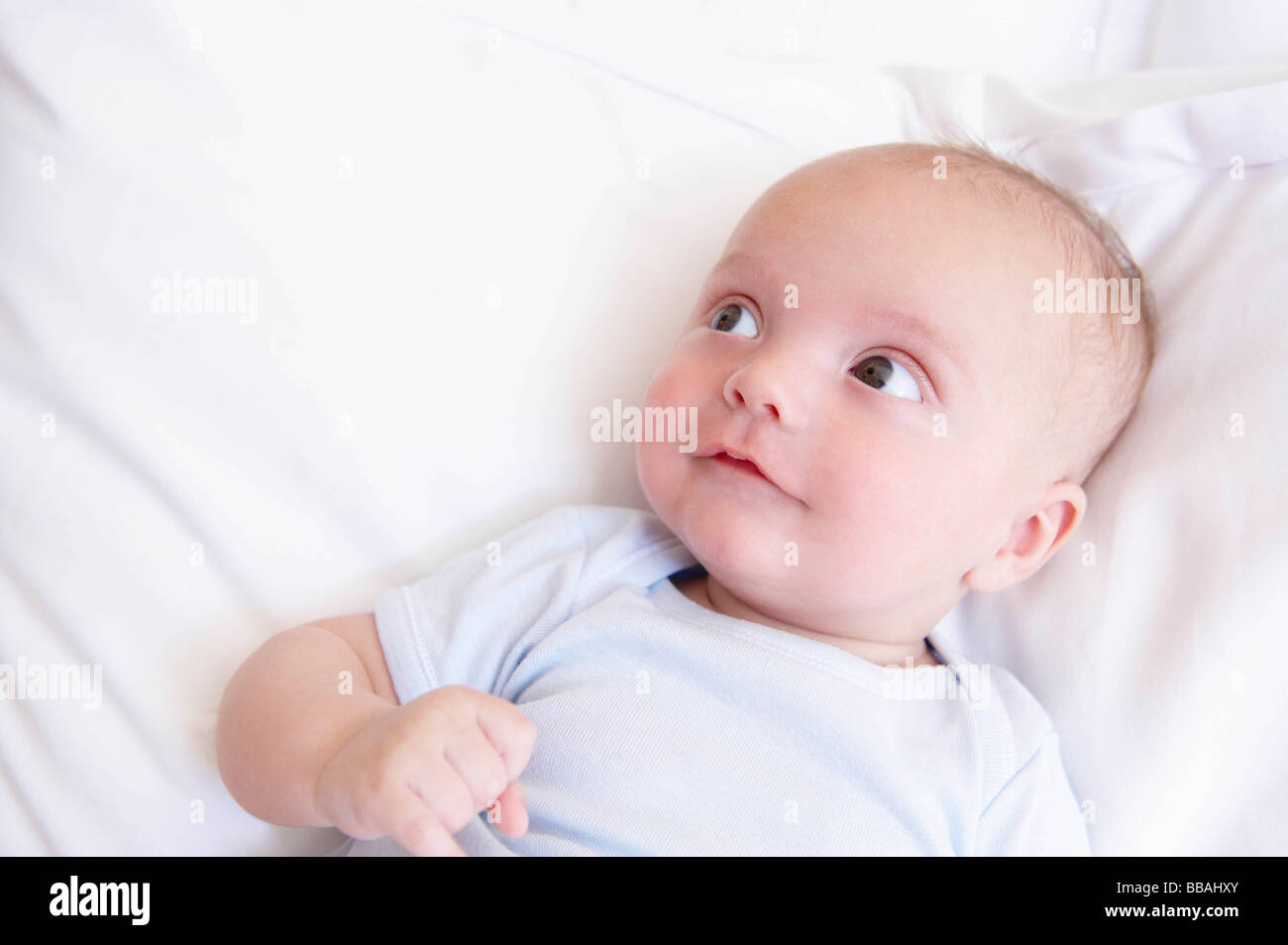 Bebé con los ojos abiertos, en la cama Foto de stock