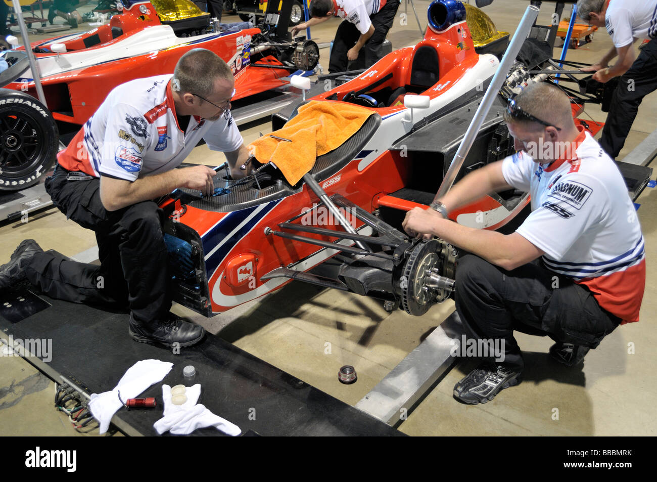 Mecánica en trabajos en coloridos coches de carreras Indy Foto de stock