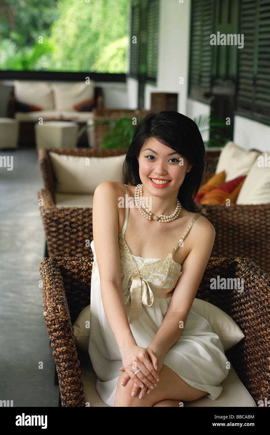 Mujer joven en vestido sin mangas sonriendo a la cámara Foto de stock