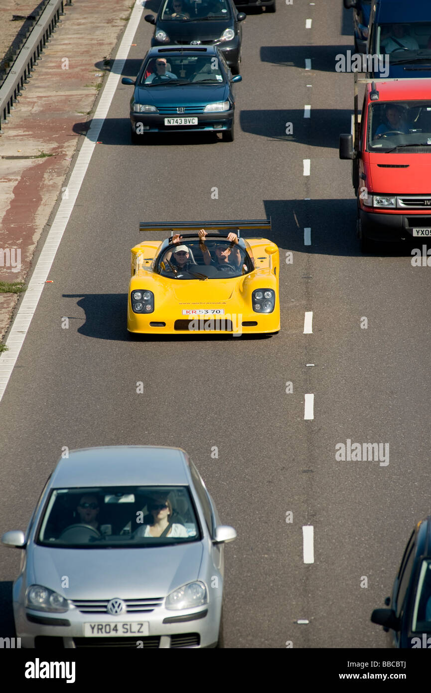 Amarillo auto deportivo convertible en cola de tráfico pesado en una autopista en Inglaterra Foto de stock