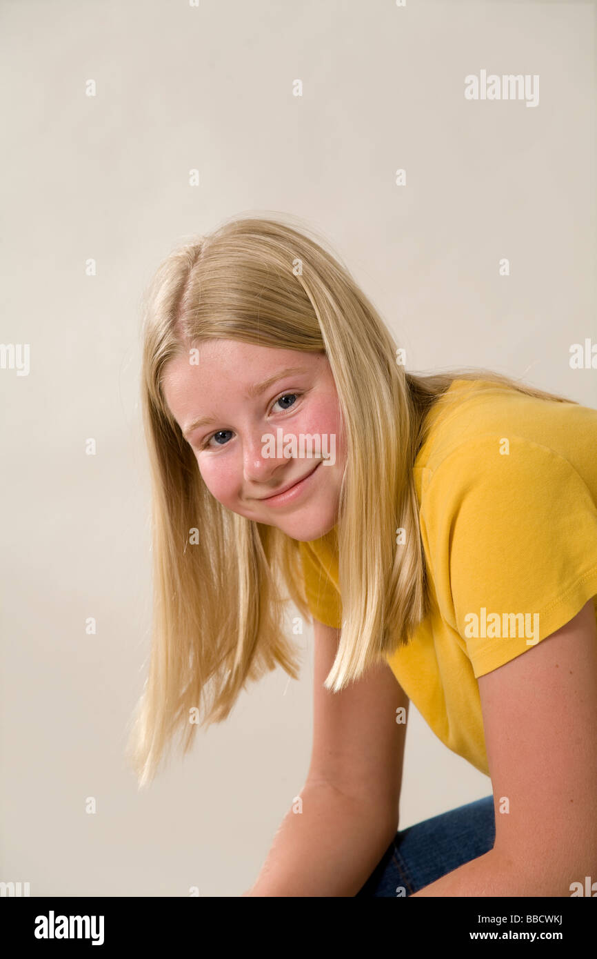 Retrato de 11-12 años de edad, niña caucásica sentado con los brazos sobre las rodillas inclinada mirando la cámara seguros casuals casualmente vestía ropa casual EE.UU. Foto de stock