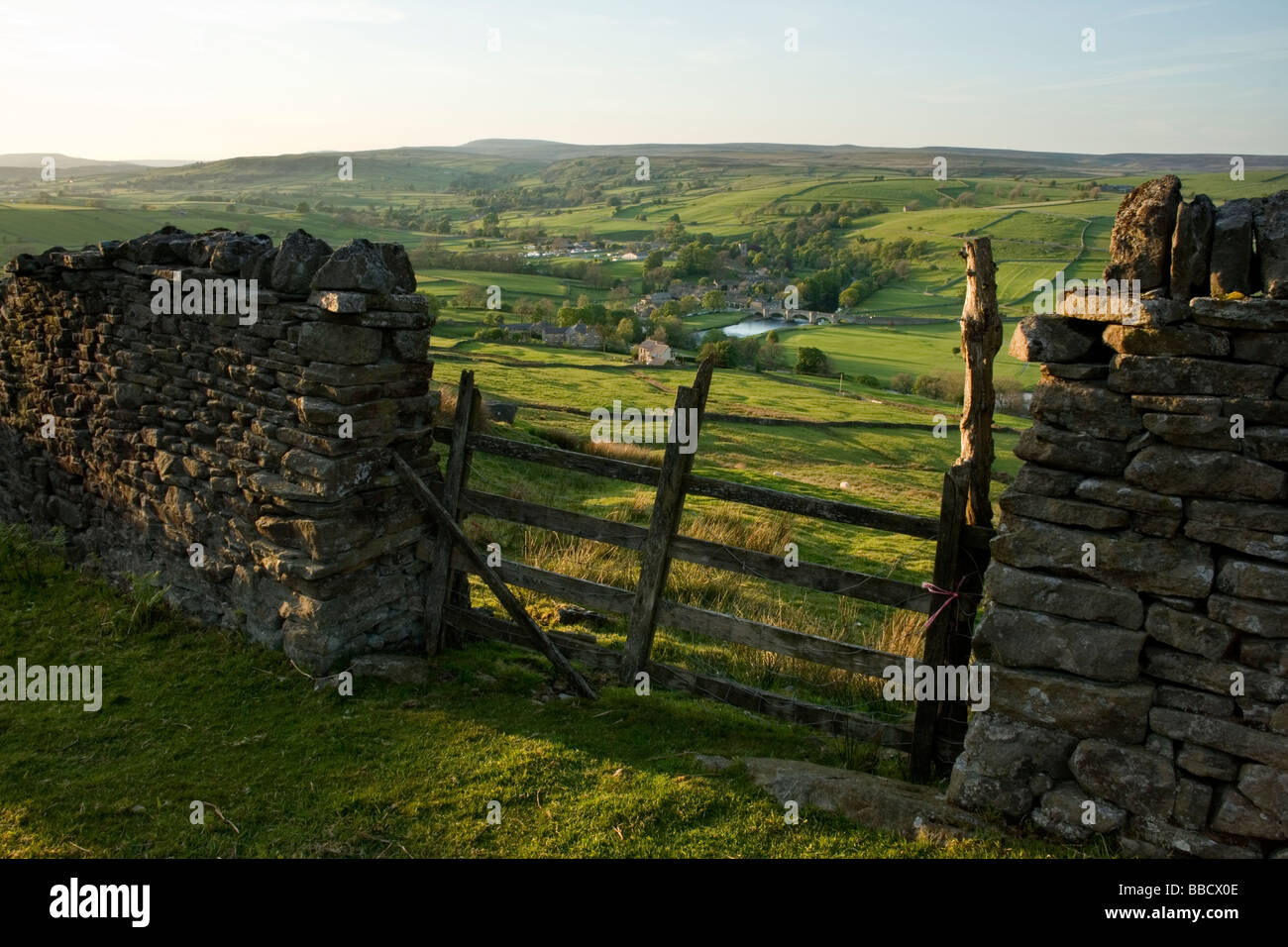 Una pared drystone enmarca la vista hacia la aldea de Burnsall, en Wharfedale, Yorkshire Dales, desde Burnsall cayó Foto de stock