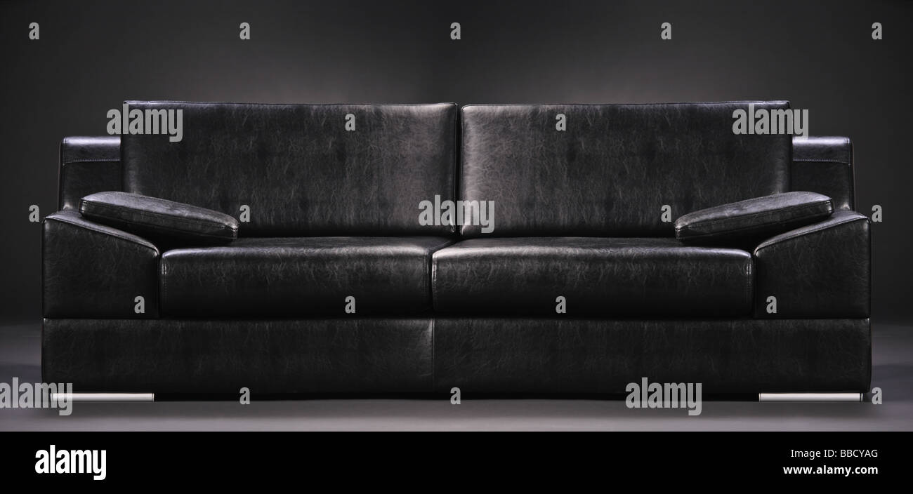 Modernos sofás negros aislados contra fondo negro Foto de stock