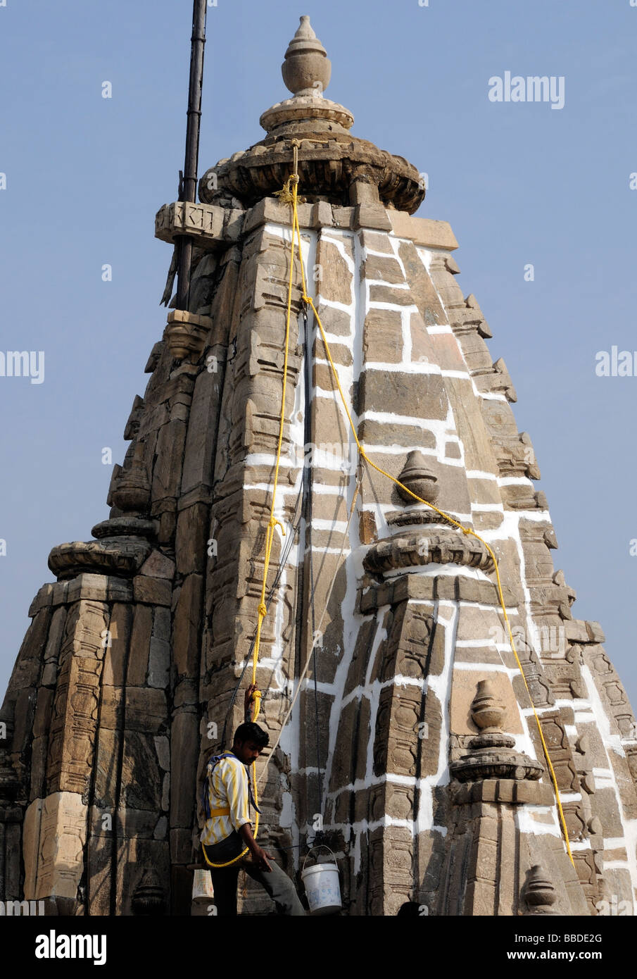 Un trabajador suspendido de cuerdas repara el trabajo de la piedra del templo Jagdish Mandir. Foto de stock