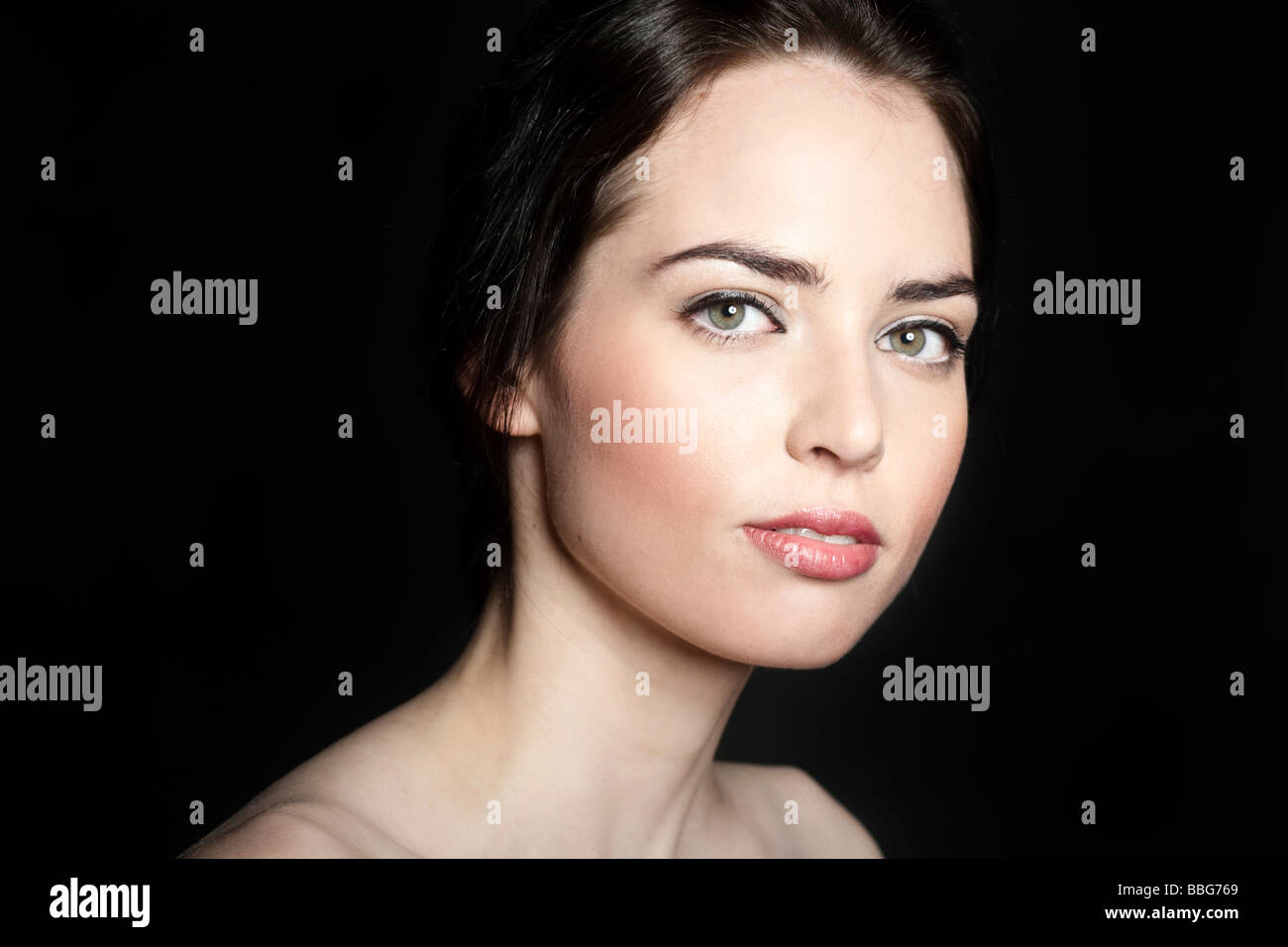 Retrato de una joven mujer morena delante del telón de fondo negro Foto de stock