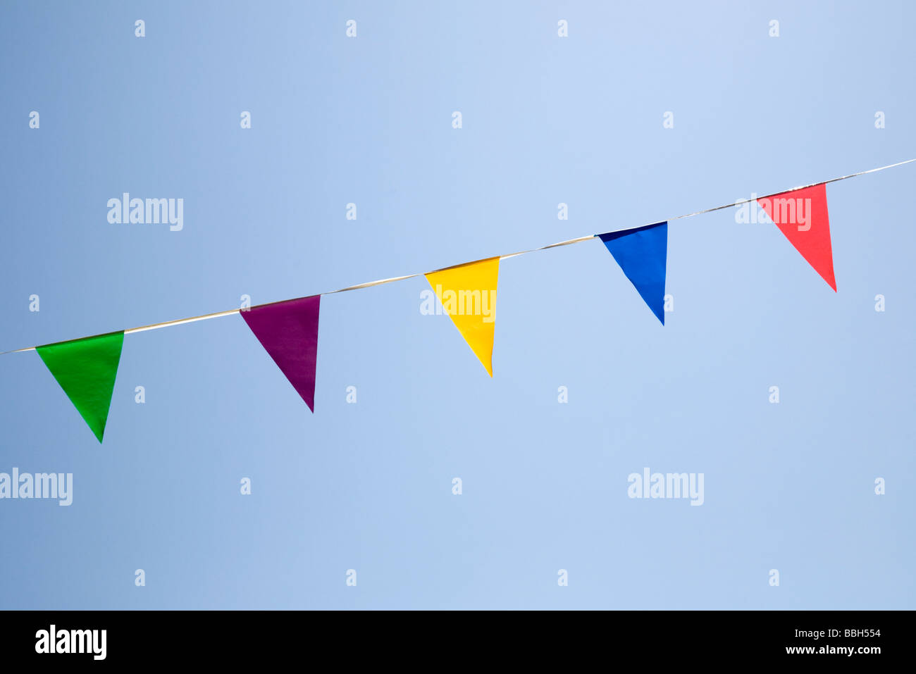 Bunting - triangular banderas de diferentes colores contra un cielo azul Foto de stock