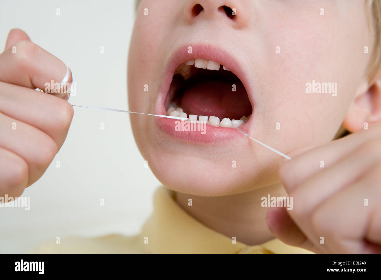 Un niño utilizando hilo dental Foto de stock