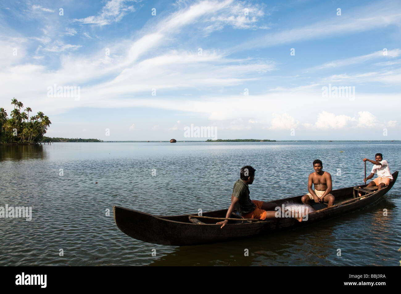 Pescador pesca en bote a remo pesca en el lago, remansos de Kerala, India Foto de stock