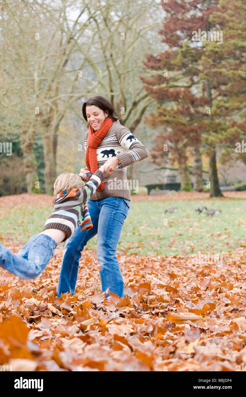 Mamá columpios hijo alrededor en hojas de otoño, Vancouver, British Columbia Foto de stock