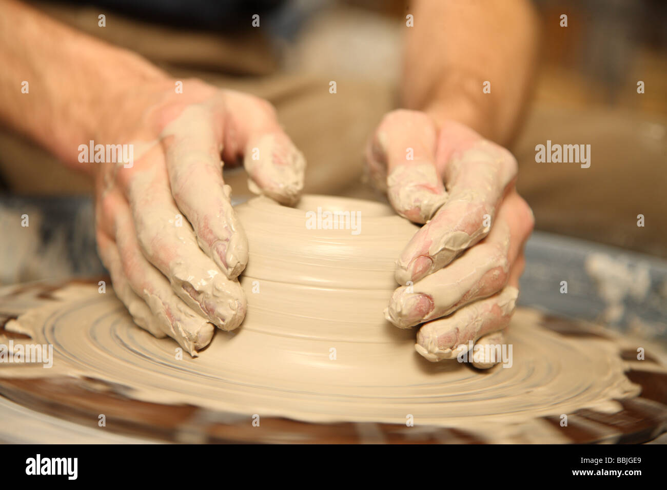 Primer plano de manos trabajando en rueda de alfarería Foto de stock
