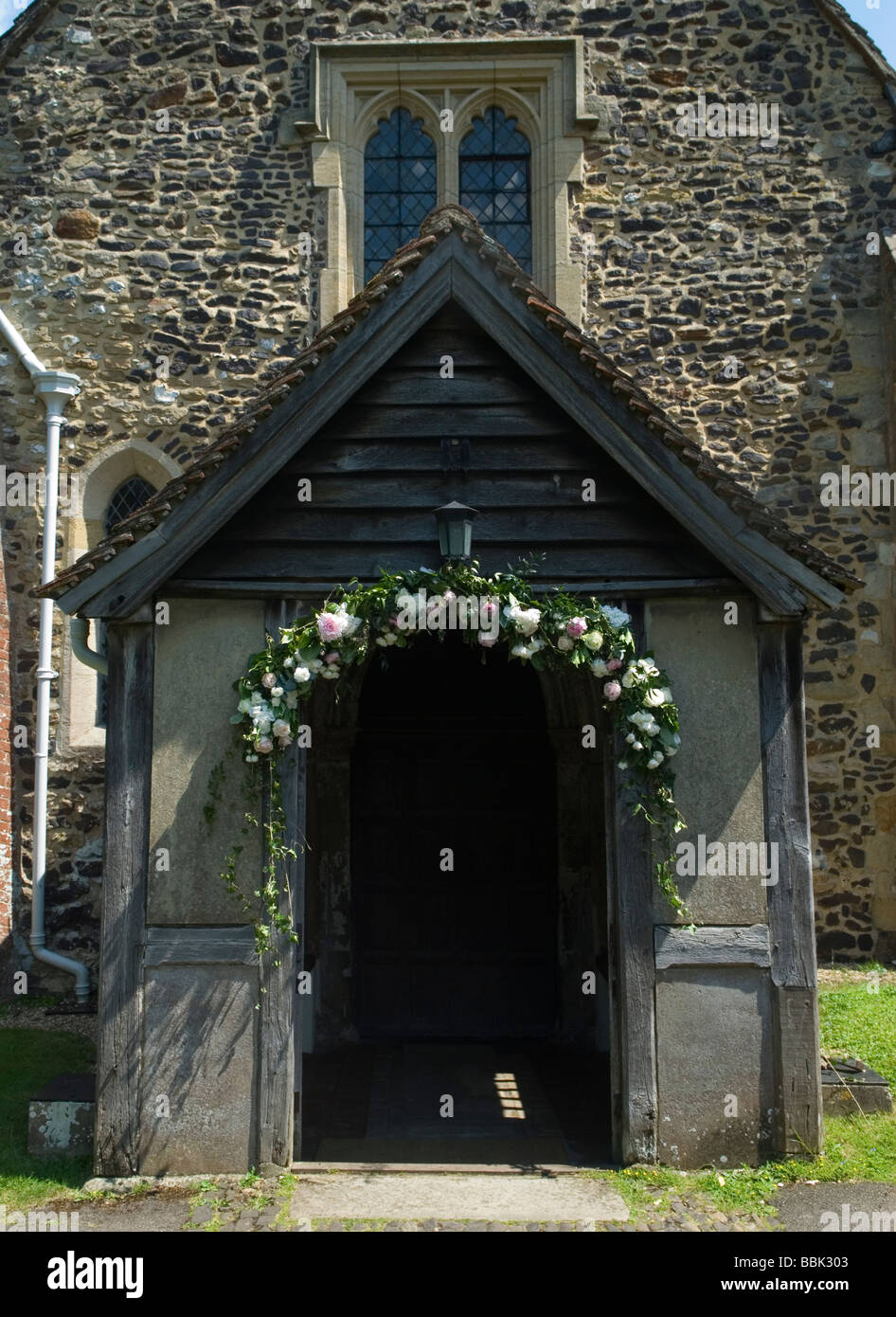 Shere Village Surrey St James Church Garland de flores sobre la puerta del porche.de la iglesia del pueblo decorado para una boda. HOMER SYKES Foto de stock