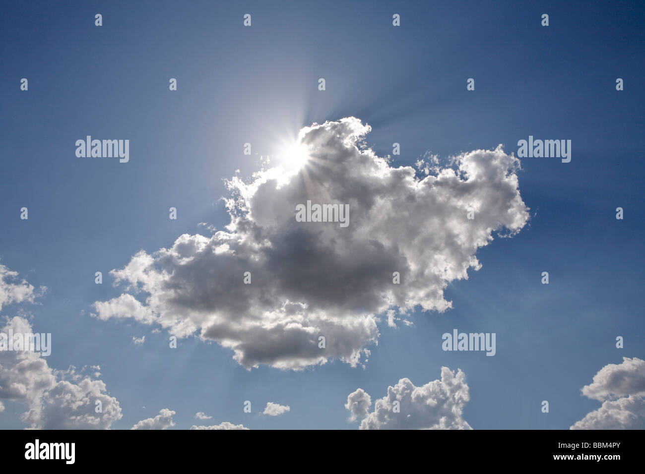 El sol detrás de una nube blanca delante de un cielo azul Foto de stock