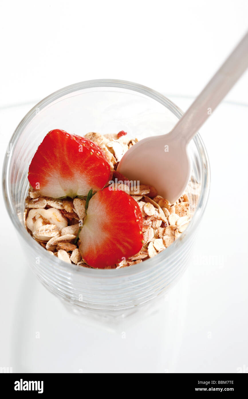 Muesli con yogur en un pequeño frasco de vidrio, fresas, yogurt cuchara Foto de stock