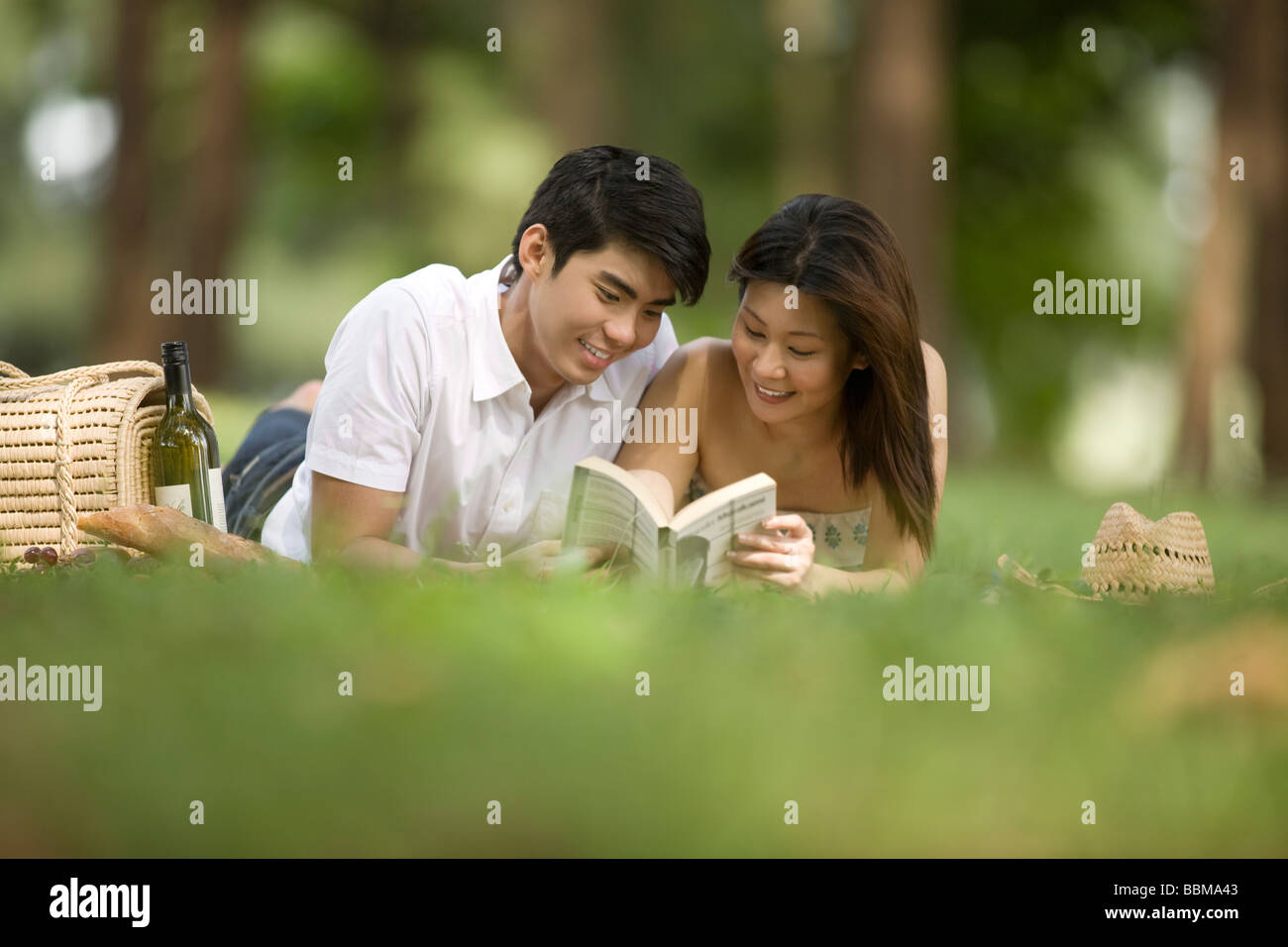 Pareja joven tener un picnic en el parque, leyendo Foto de stock