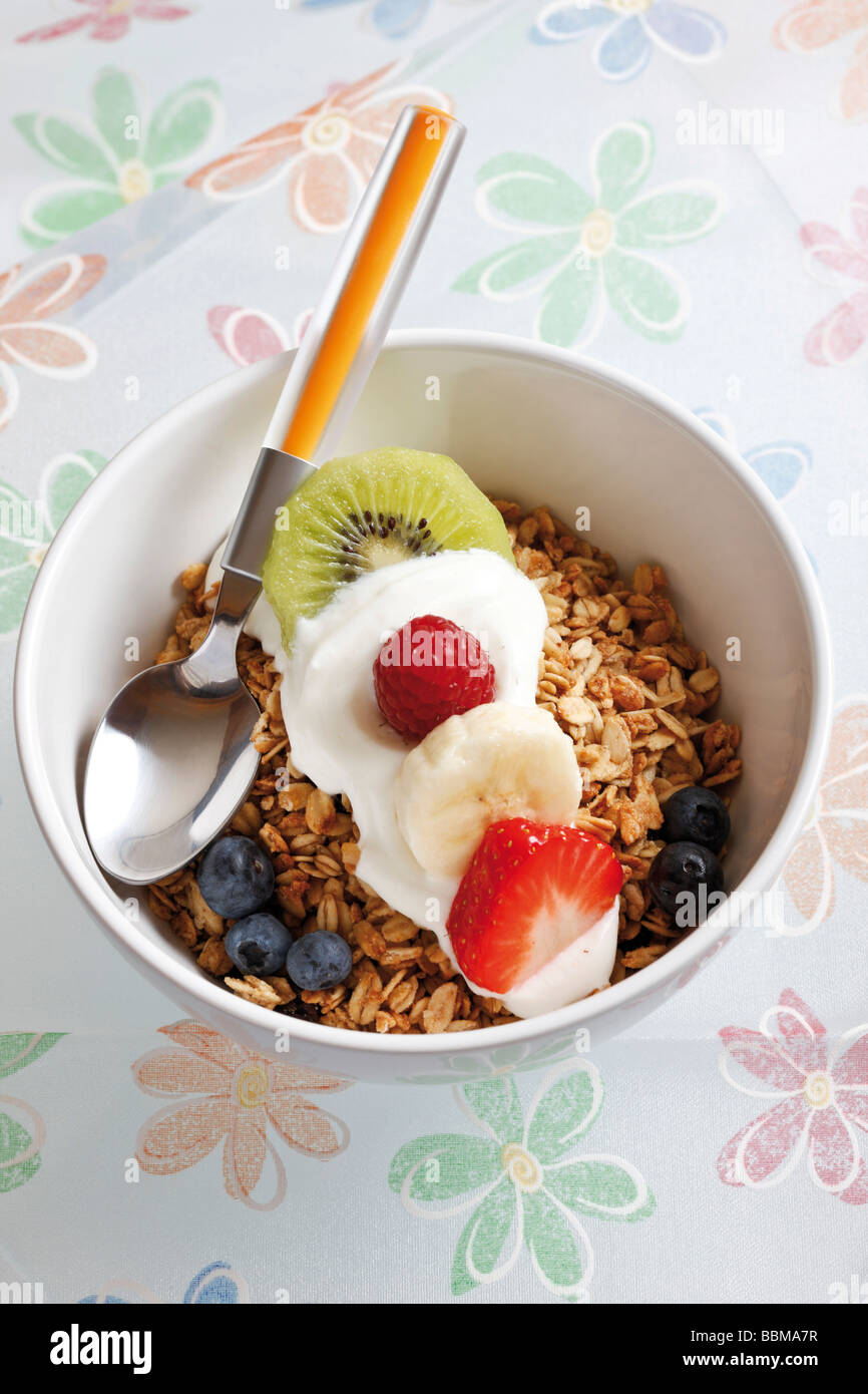 Muesli con yogur y fruta en un tazón de porcelana, kiwi, frambuesa, fresa y arándanos Foto de stock