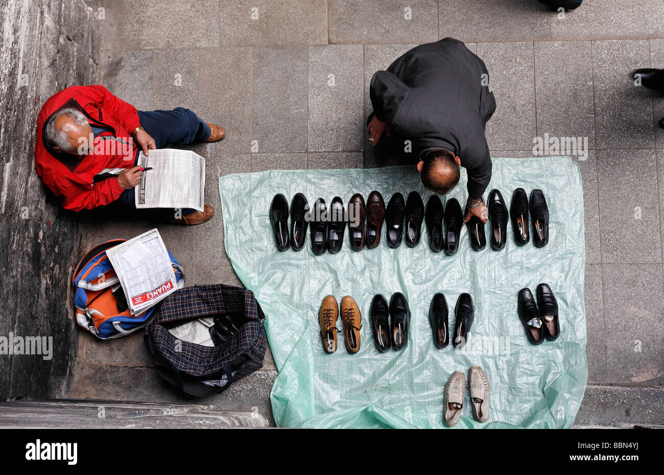 Mann vende zapatos usados en la calle, un cliente alcanza para un zapato, vista desde arriba, Estambul, Turquía Foto de stock