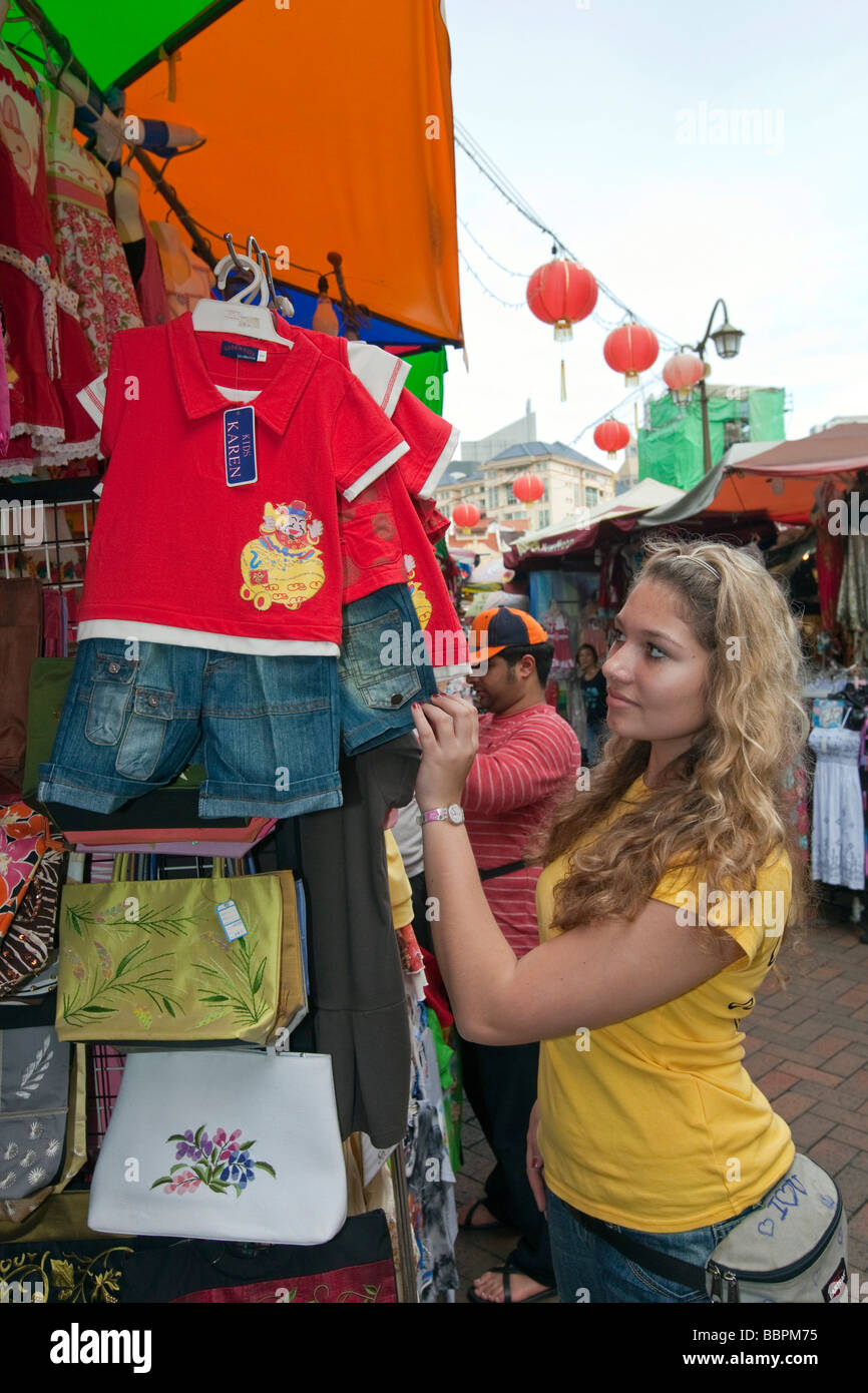 Turista está interesado en un vestido, Chinatown, el colorido mercado como una atracción turística, la calle Temple Street, Singapur, Sudeste de Asia Foto de stock