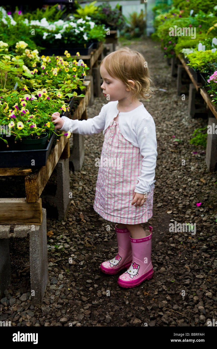 Niña en rosa botas en un vivero de plantas mirando las flores Fotografía de  stock - Alamy