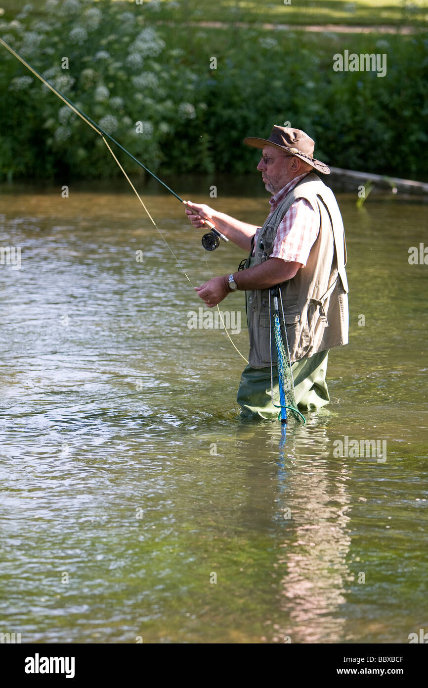 Pescador con mosca vadeando en Arroyo de truchas Foto de stock
