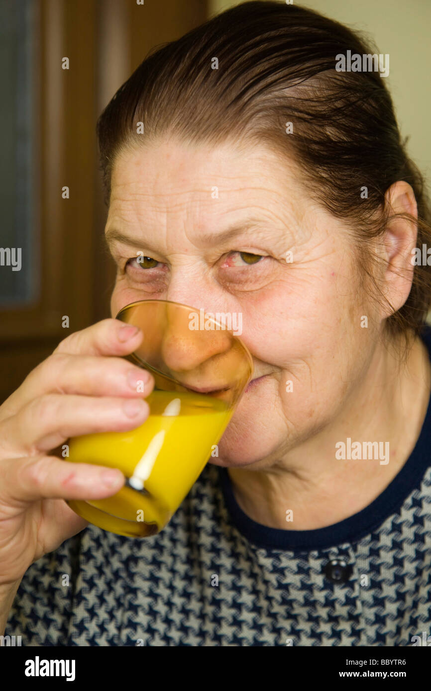 Mujer de 67 años de edad, tomar jugo de naranja Foto de stock