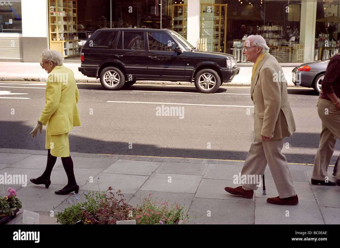 Una acomodada pareja de ancianos bien vestido caminando por la calle Kings Road en otoño de sol Foto de stock