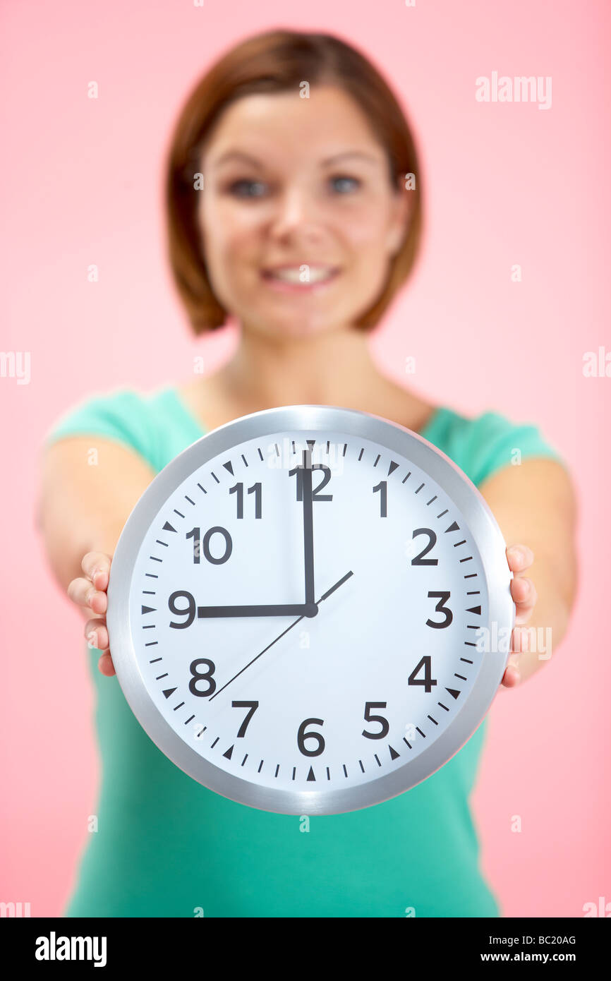 Mujer sosteniendo reloj mostrando 9 O'Clock Foto de stock