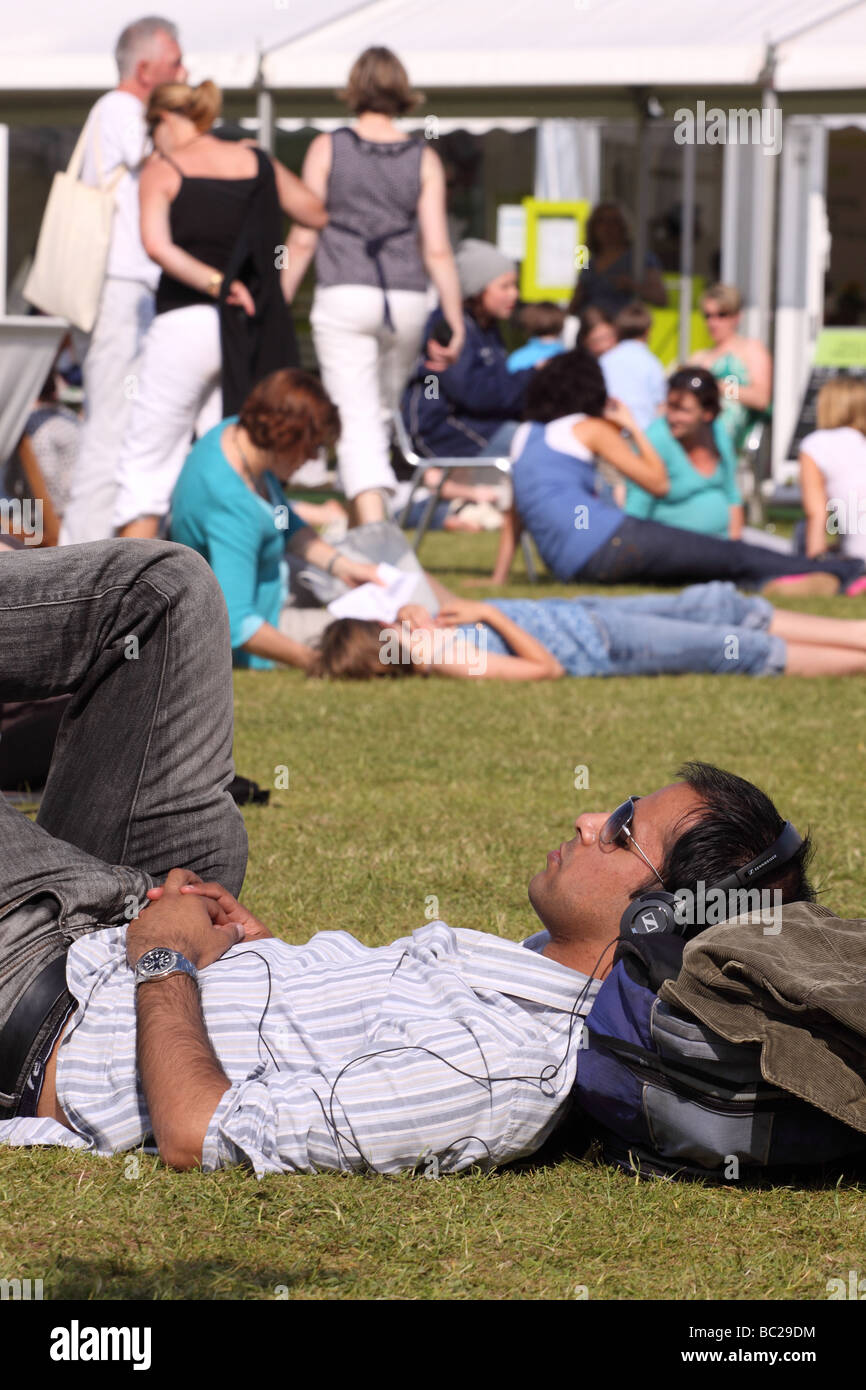 Hay Festival hombre relajarse escuchando música de auriculares en el césped natural en el Festival del heno de mayo de 2009 Foto de stock