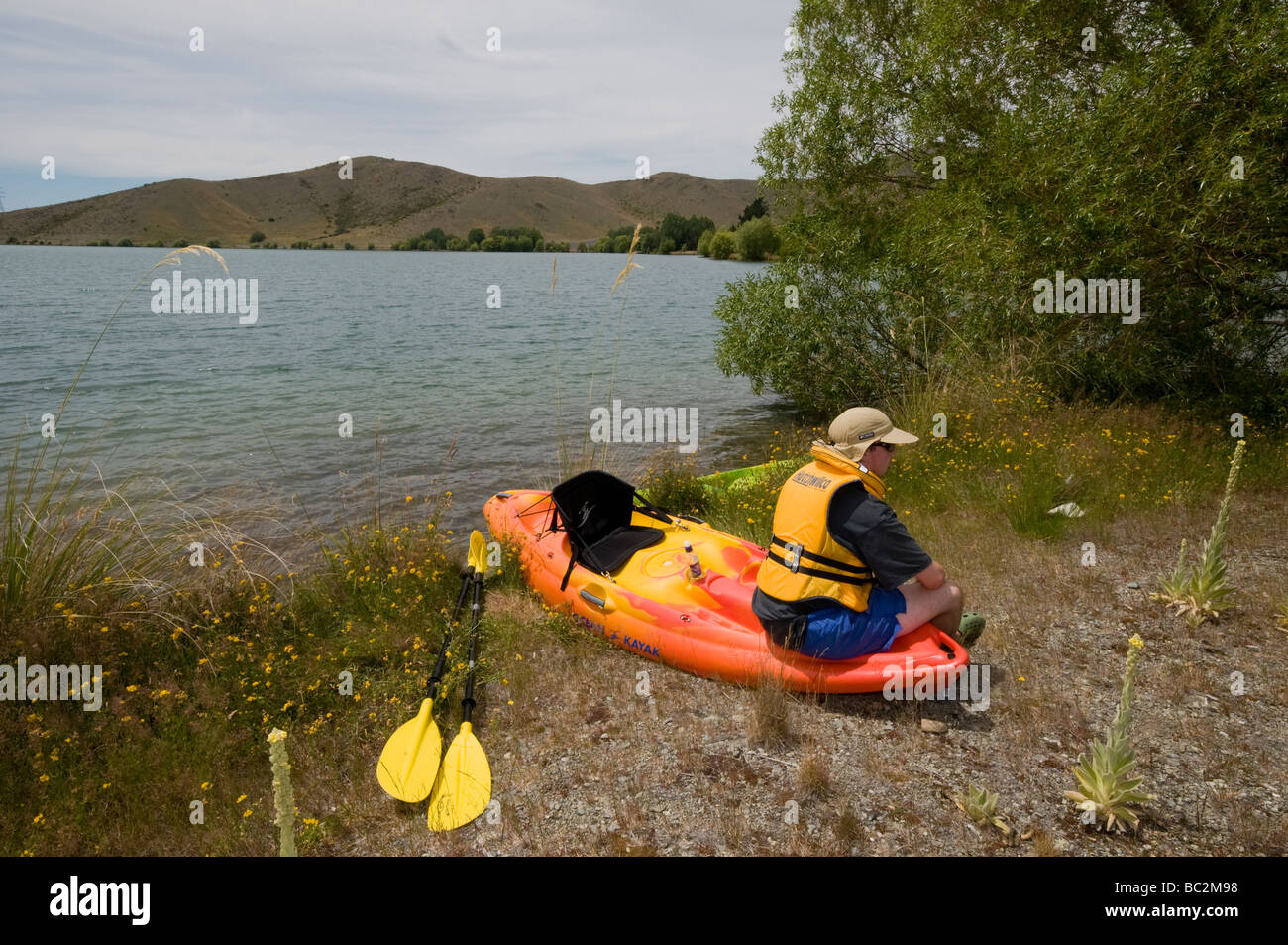 Adolescente descansando con kayak por el brazo del lago Ruataniwha Wairepo, cerca de Twizel Foto de stock