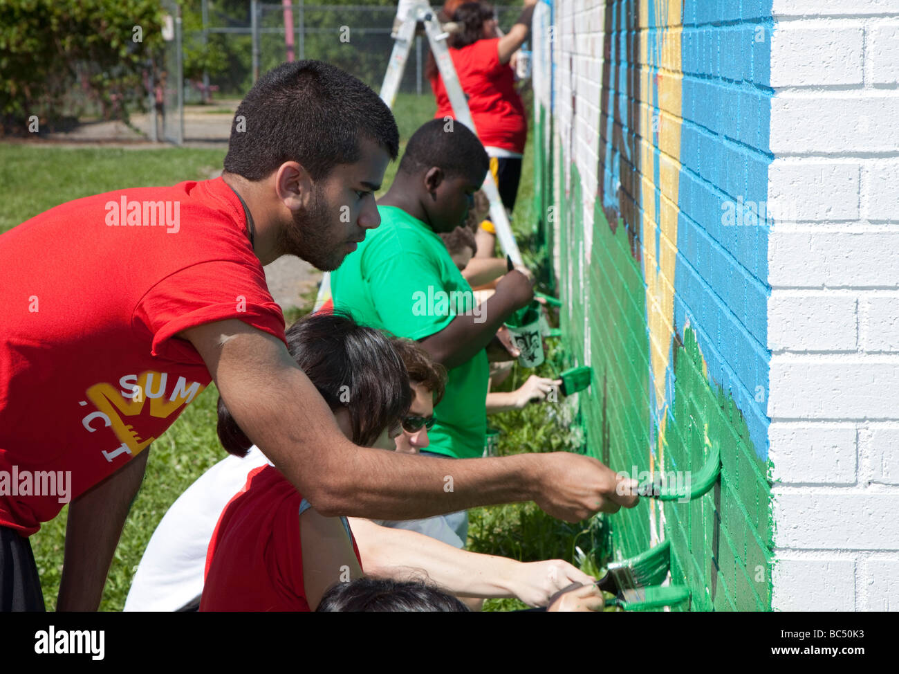Jóvenes voluntarios Pintar pared en City Park Foto de stock