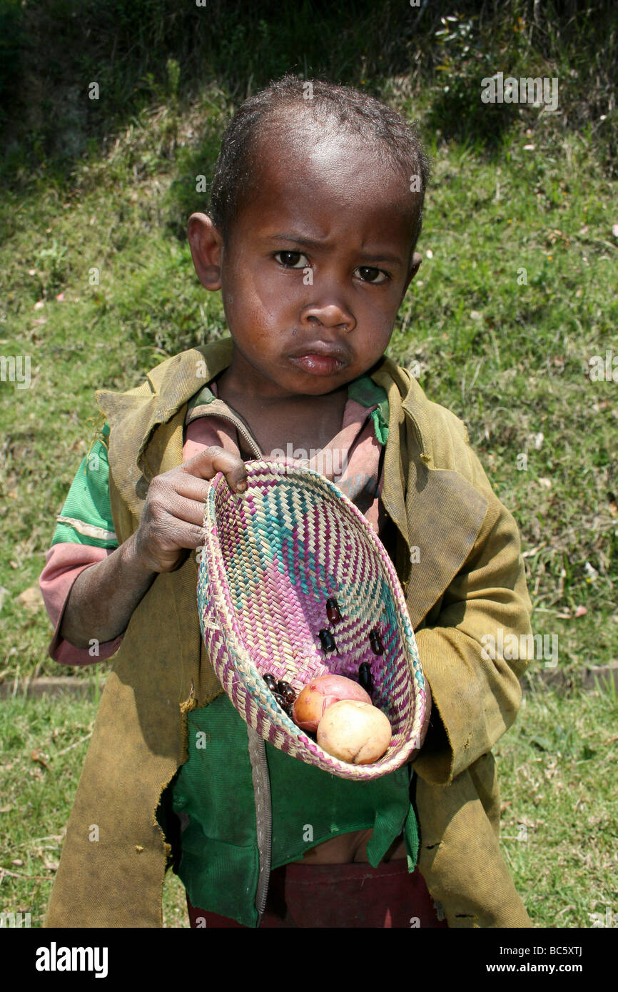 Madagascar joven niño sosteniendo cesta tejida que contienen frutas y Scarab escarabajos Foto de stock