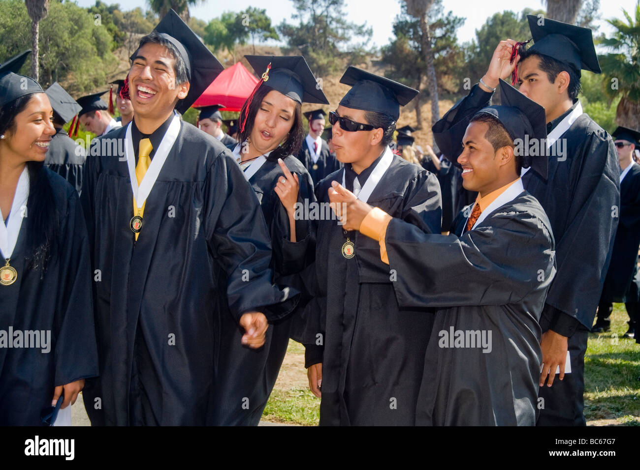 En su graduación de la escuela secundaria ejercicios en Costa Mesa, California, el director de la escuela le da un abrazo de felicitación a un estudiante hispano de graduación. Foto de stock