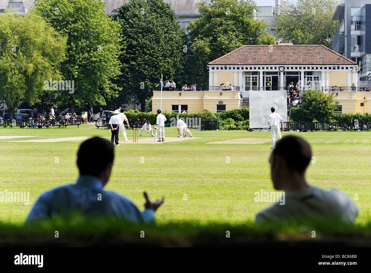 Los espectadores viendo un partido durante el almuerzo en el Trinity College de cricket club jardines en el centro de Dublín, República de Irlanda Foto de stock