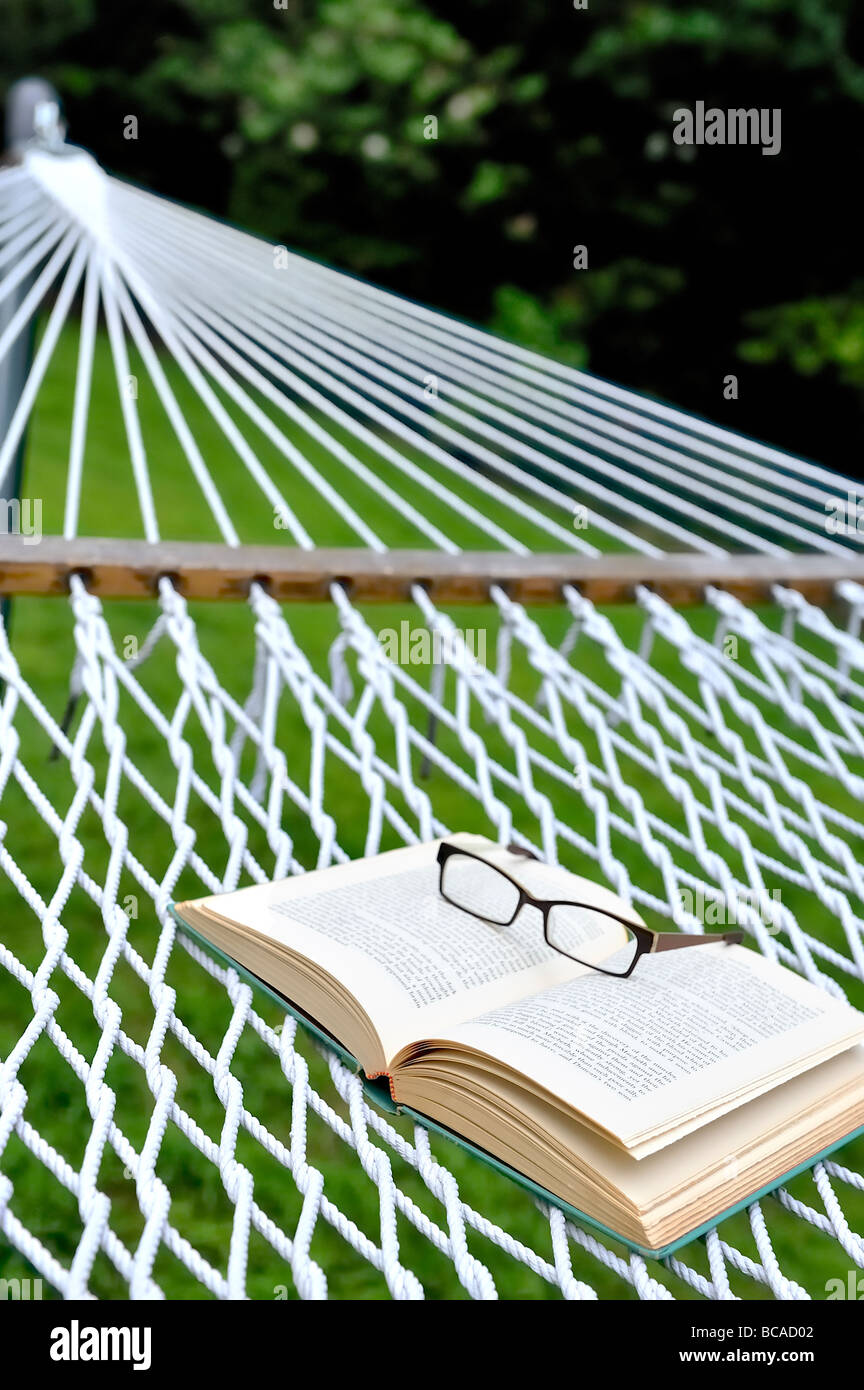 Lectura de verano vacaciones de fin de semana de retiro staycation inicio concepto gafas Gafas gafas hamaca traspatio de libro abierto. Foto de stock