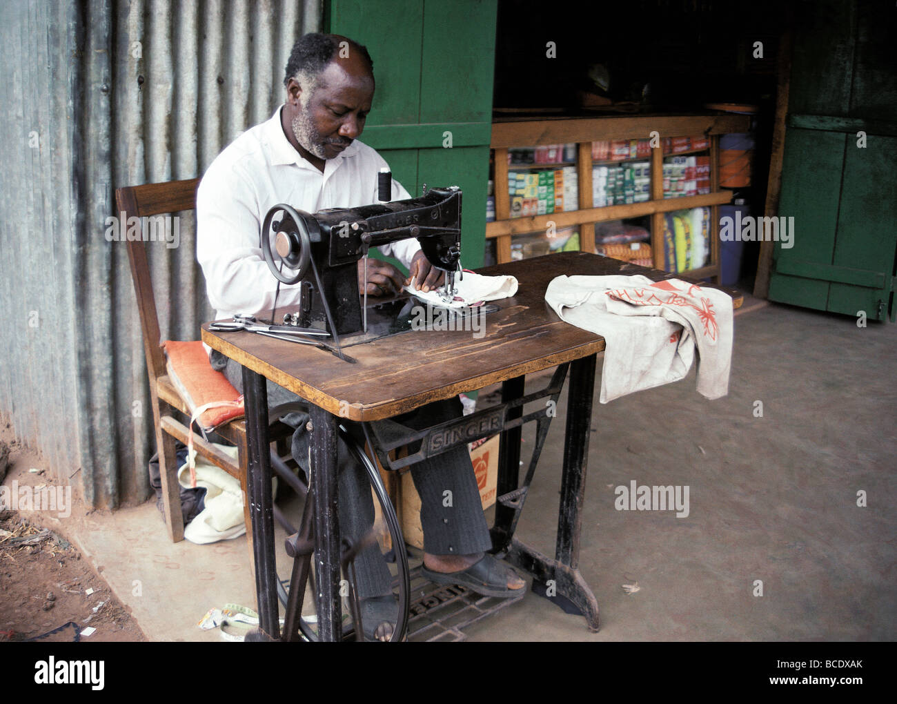 El hombre negro africano adaptar la máquina de coser Singer de pedal de  trabajo al lado de la carretera almacenar Uganda África Oriental Fotografía  de stock - Alamy