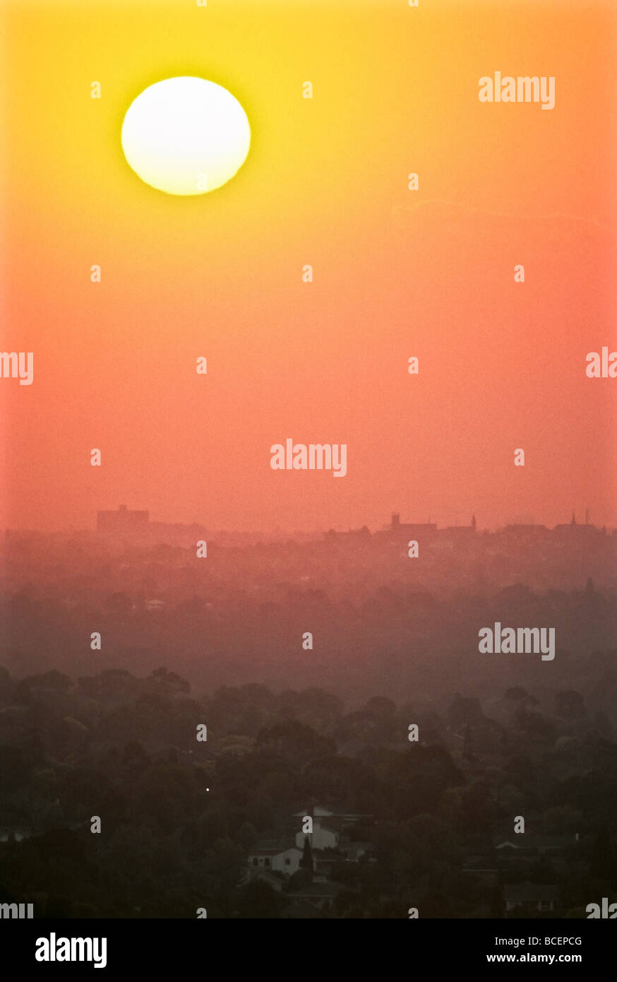 Puesta de sol penetra en una neblina de contaminación asentados sobre una expansión urbana de las ciudades. Foto de stock