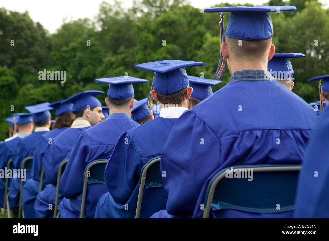 Los estudiantes de secundaria vestido de azul y oro y birrete asistir a la ceremonia de graduación en EE.UU. Foto de stock