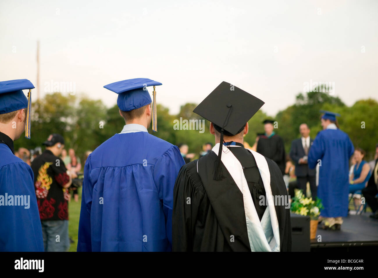 Los estudiantes de secundaria vestido de azul y oro y birrete asistir a la ceremonia de graduación en EE.UU. Foto de stock