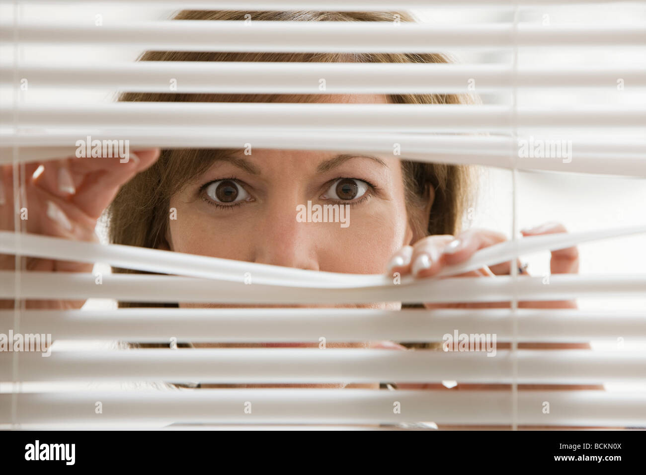 La empresaria mirando a través de las persianas Fotografía de stock - Alamy