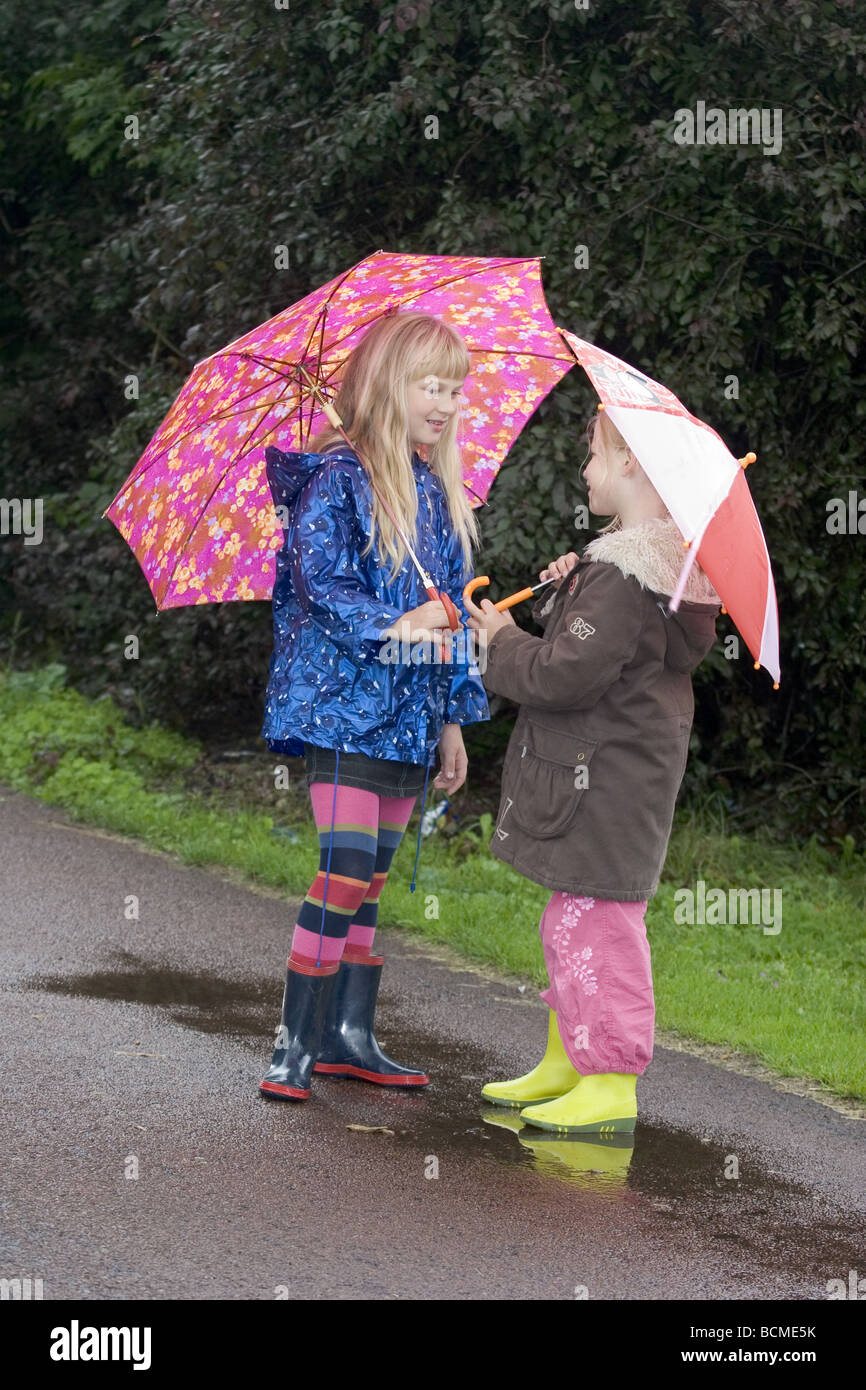 Amiga de la infancia fuera en la lluvia con el paraguas feliz charlando y  buddy hasta después de la escuela Fotografía de stock - Alamy