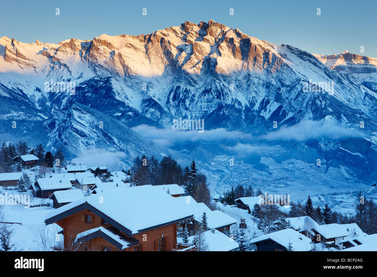 Un nuevo nevadas en la aldea alpina de La Tzoumas al amanecer, con Iserables y valle del Ródano, más allá de la región de Valais, Suiza Foto de stock