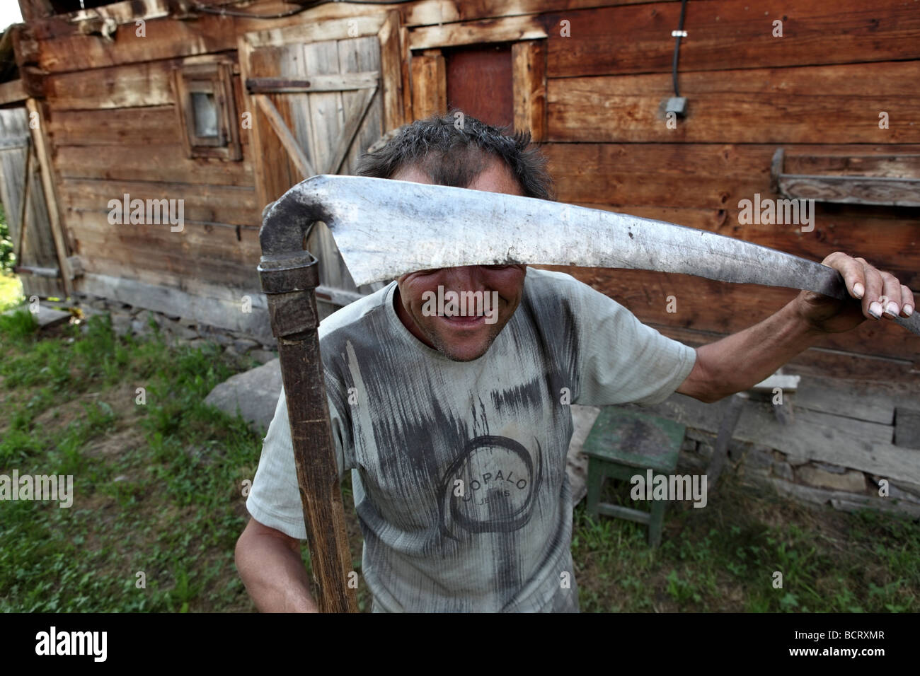 Un campesino rumano posa con su guadaña delante de la cámara. Foto de stock
