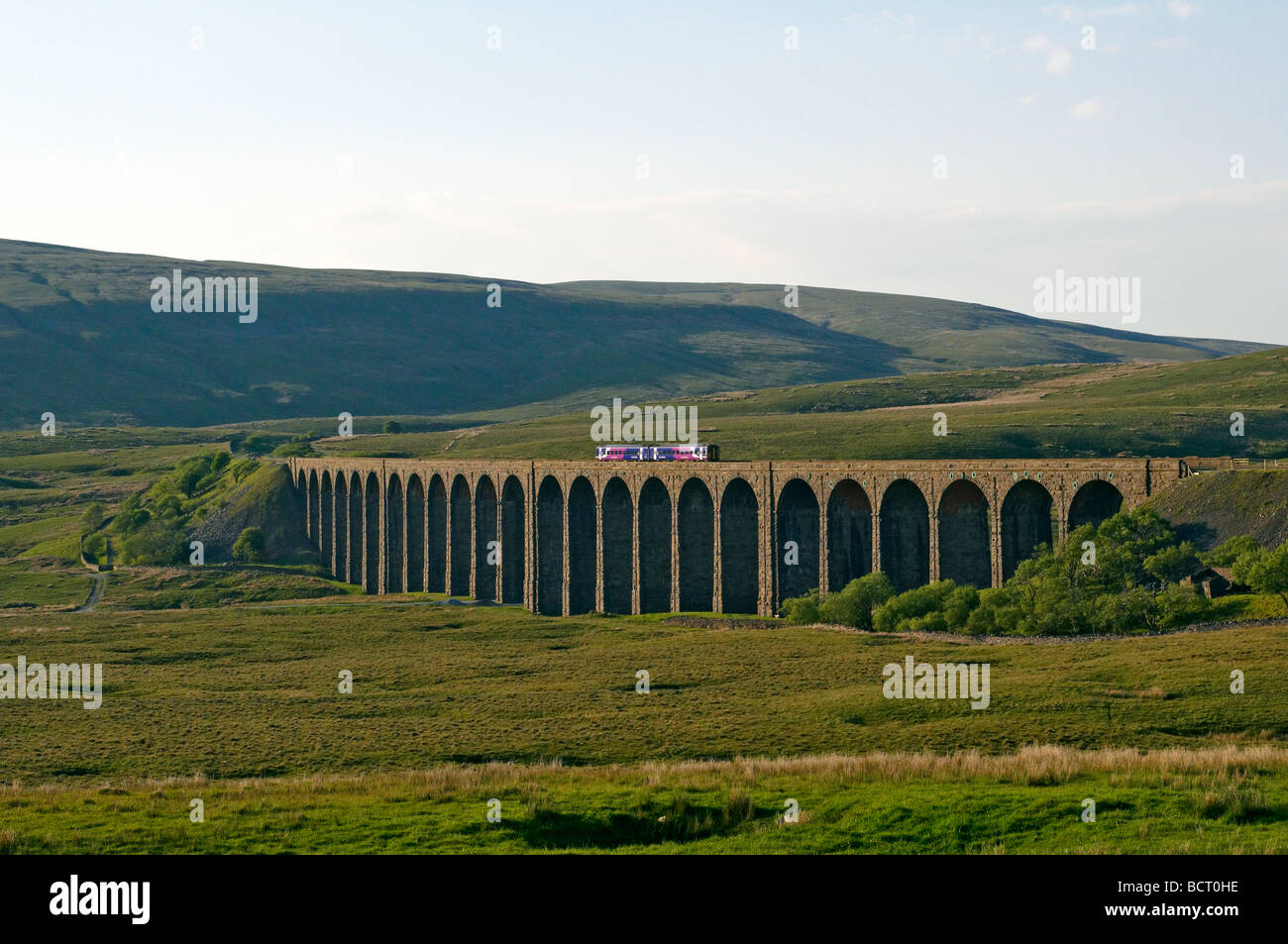 La Ribblehead Viaduct en los valles de Yorkshire con un pequeño tren que cruza el viaducto Foto de stock