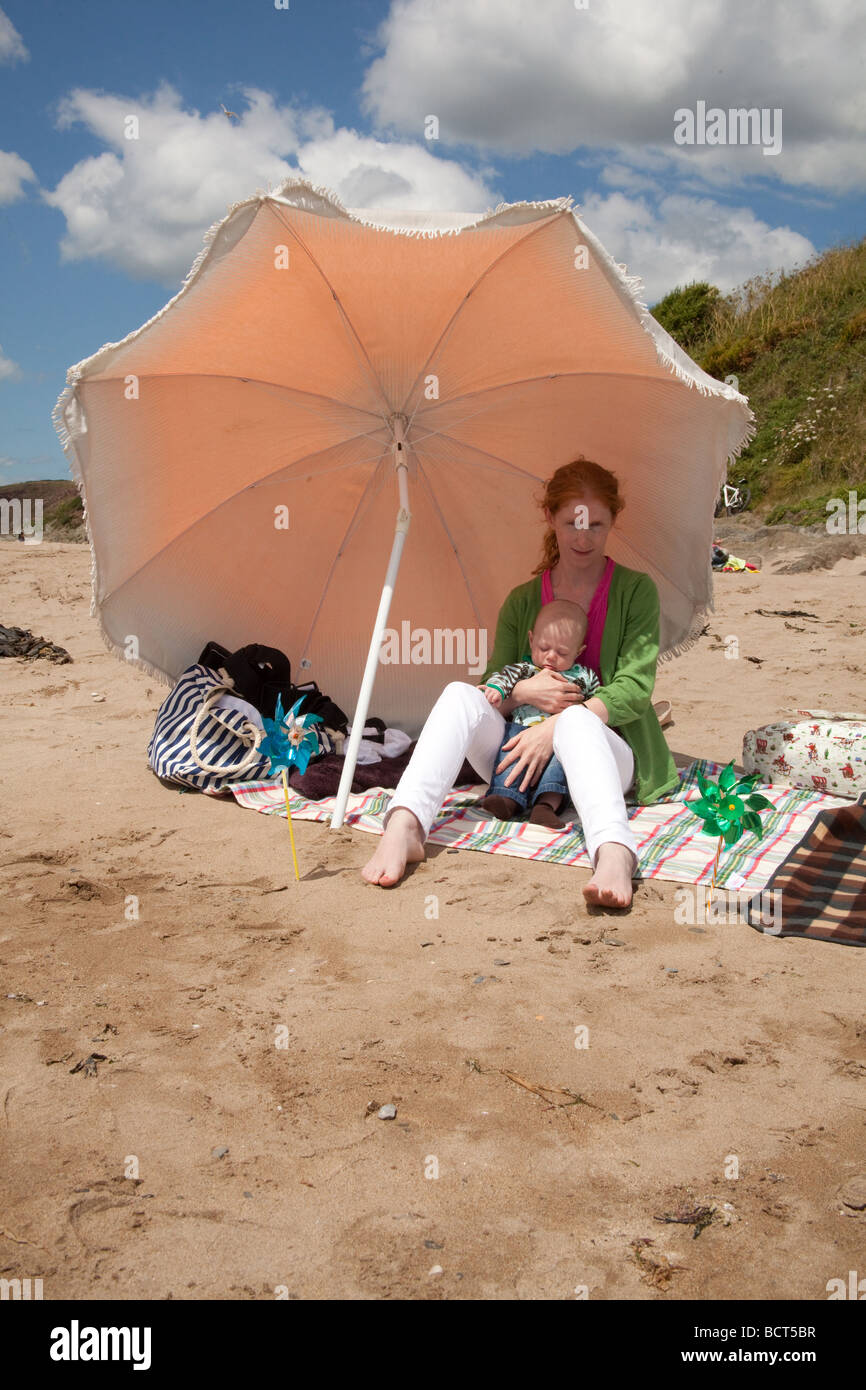 Madre mes bebé viejo en la playa bajo parasol fotografías e imágenes de  alta resolución - Alamy