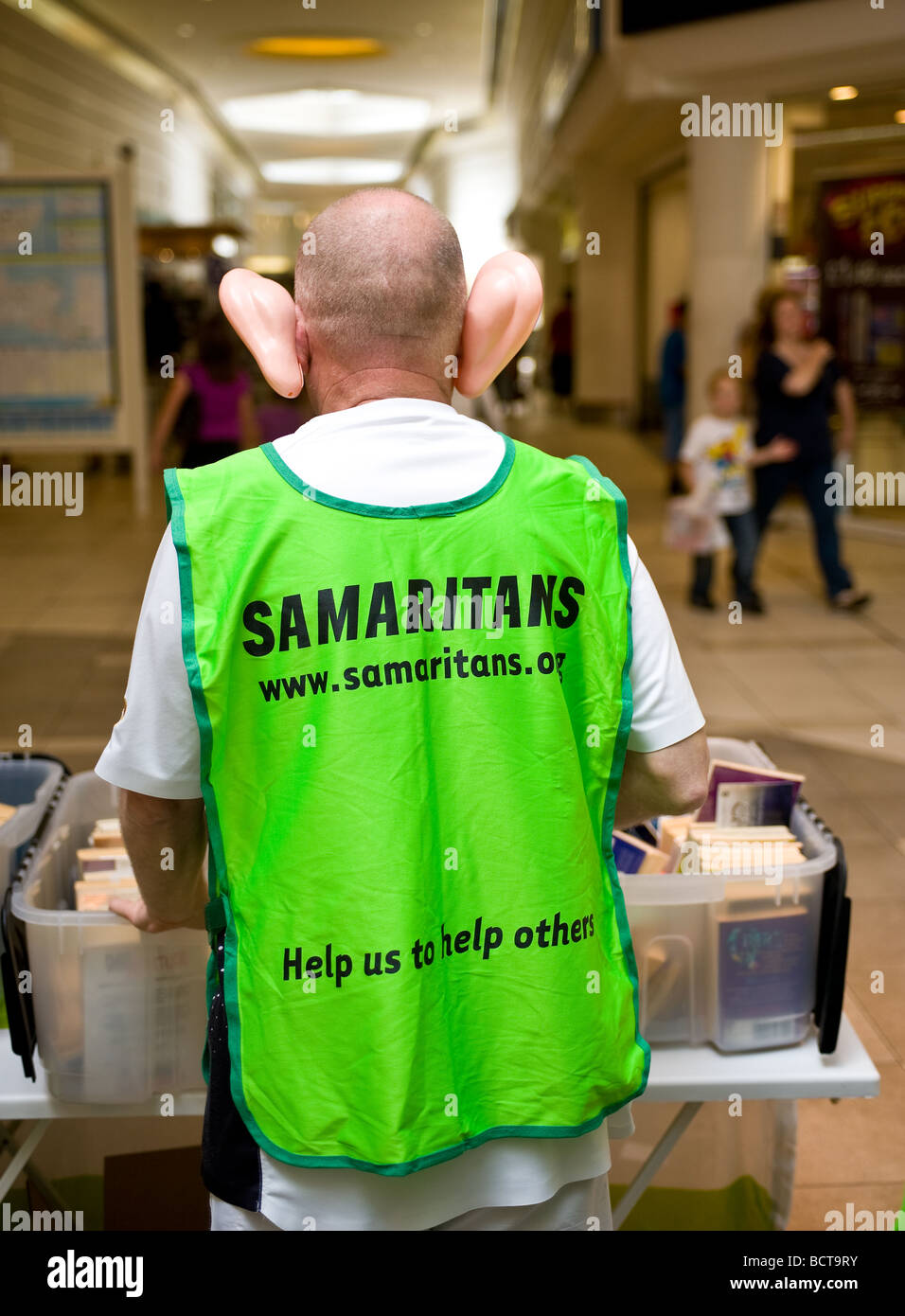 Un voluntario de la organización benéfica Los Samaritanos recaudando fondos mientras llevaban grandes y falsas orejas de plástico. Foto de stock