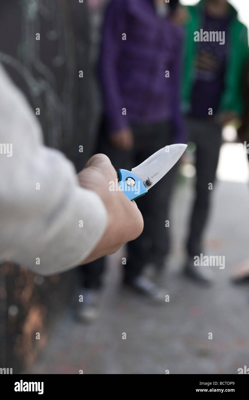 Adolescente amenazando a un grupo con un cuchillo Foto de stock