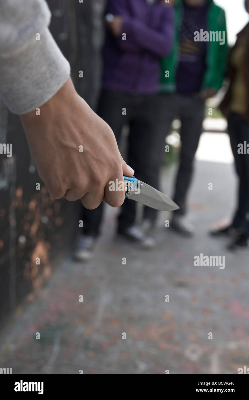 Adolescente amenazando a un grupo con un cuchillo Foto de stock