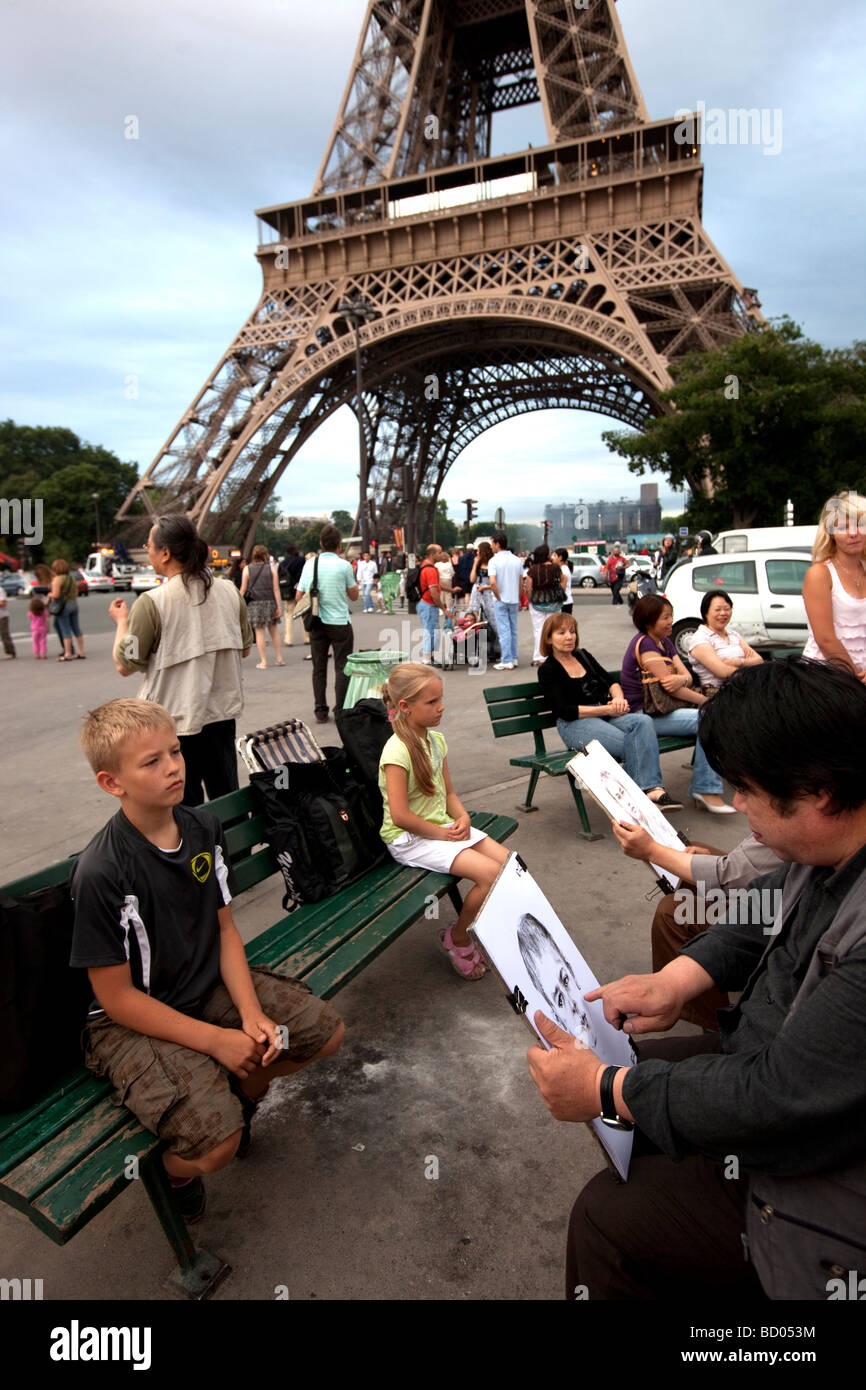 Delante de la torre Eiffel, algunos niños son, posando para un retratista Foto de stock