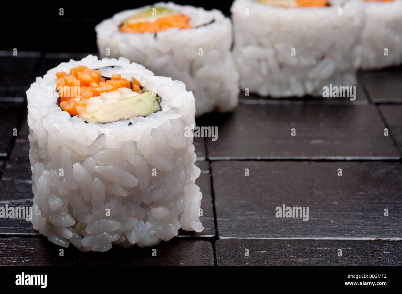 Un enfoque macro superficial horizontal de sushi sobre un fondo de madera negra Foto de stock