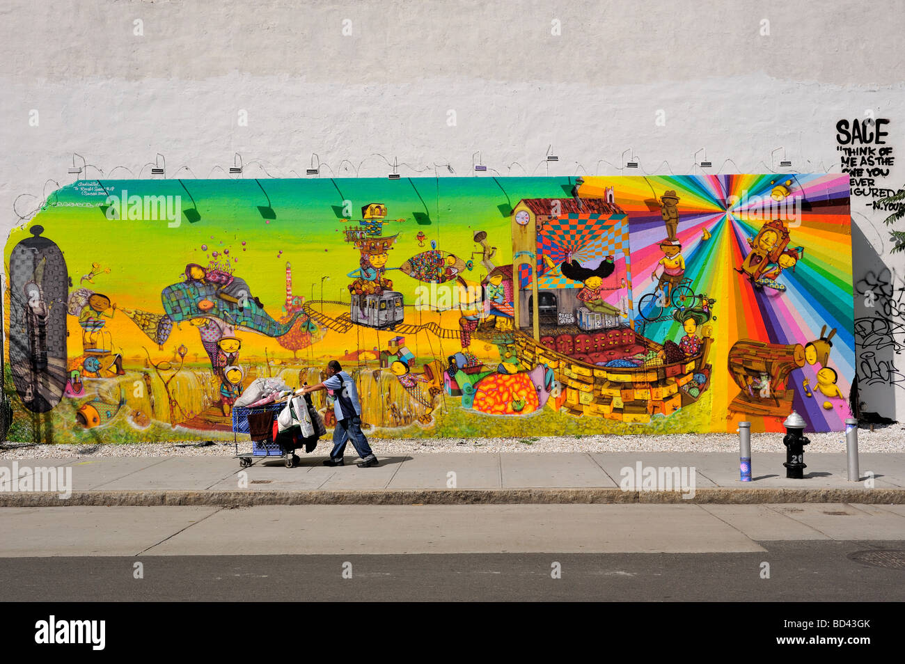 Hombre sin hogar pasa delante del os Gemeos mural en Bowery y Houston en la Ciudad de Nueva York. Foto de stock